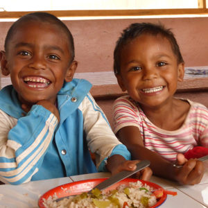 zwei strahlende madagassische Kinder beim Essen
