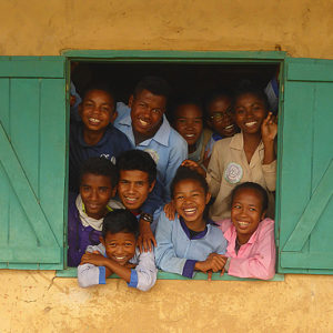 madagassische Jugendliche gucken aus einem Zimmerfenster mit Fensterläden und lachen im Bildungszentrum Alabri