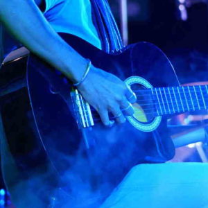 junger Mann mit Gitarre in blauem Bühnenlicht